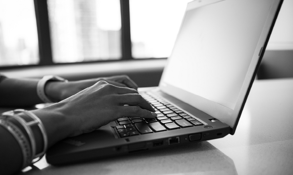foto preto e branco de pessoa usando o computador com foco apenas nas mãos