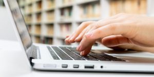 Mãos brancas digitando em um notebook para simular a imprensa oficial ms