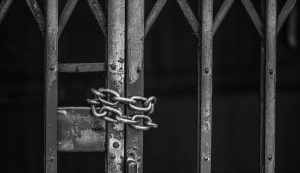 Portão de prisão trancado com corrente, simbolizando o livramento condicional.