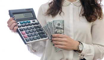Mulher de branco segurando uma calculadora e notas de dinheiro, representando o patrimônio líquido de uma empresa.
