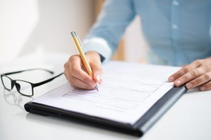 Empresária assinando documento para participar de licitações públicas.