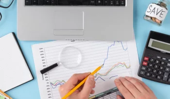 Imagem de uma mesa com objetos de escritório e uma pessoa realizando um planejamento tributário