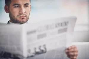 Homem lendo jornal físico antes de pesquisar sobre o Diário online Recife
